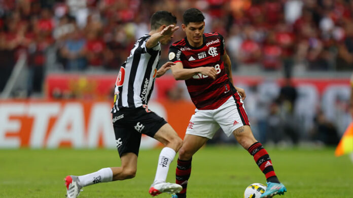 Dois jogadores de futebol brigando pela bola em um campo.