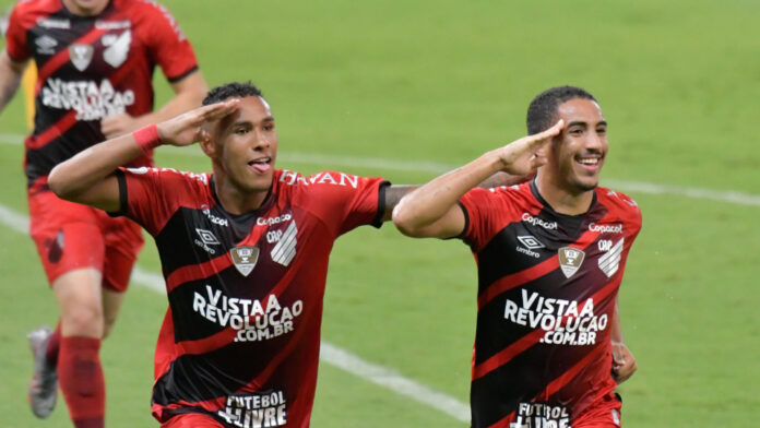 Dois jogadores de futebol comemoram um gol em um campo de futebol.