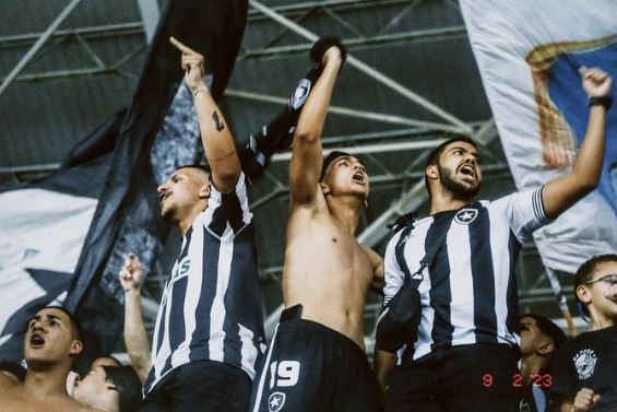 Torcedores entusiasmados do Botafogo torcendo nas arquibancadas.