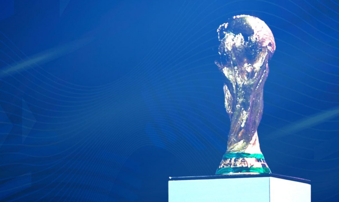 O troféu da Copa do Mundo da FIFA está em exibição em frente a um fundo azul.