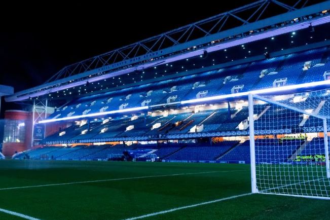 Um campo de futebol Palpite Rangers x Betis iluminado à noite.