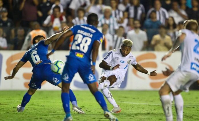 Os jogadores de futebol do Brasileiro da Série A estão em ação durante uma partida noturna, com um jogador tentando um chute de bicicleta enquanto outros assistem.