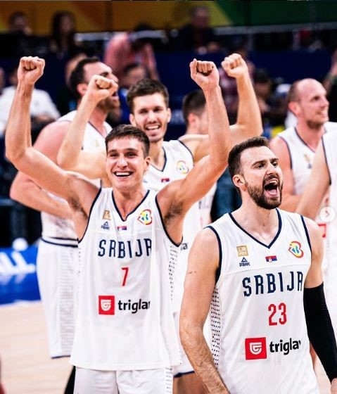 Um grupo de jogadores de basquete da Sérvia e da Alemanha comemorando na quadra.