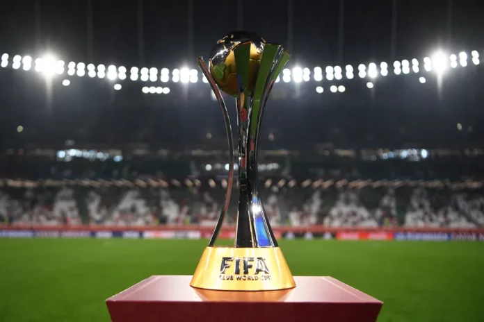 O troféu do Mundial de Clubes 2023 está sobre uma mesa em frente a um estádio.