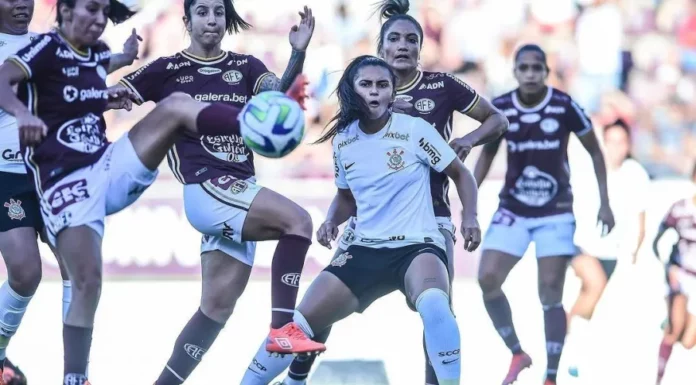 Um grupo de jogadoras de futebol do Corinthians e da Ferroviária chuta a bola.