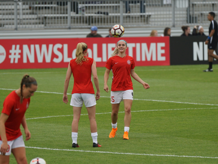 jogadoras de futebol feminino usando uniforme vermelho em campo.